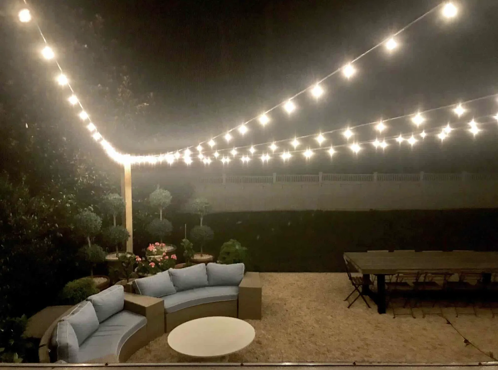Backyard patio with bistro string lights over a seating area and dining table