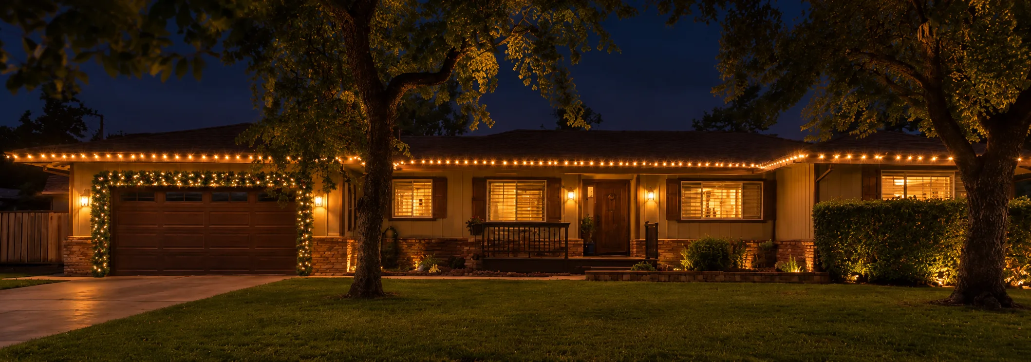Ranch home with warm white roofline and lit garland around the garage
